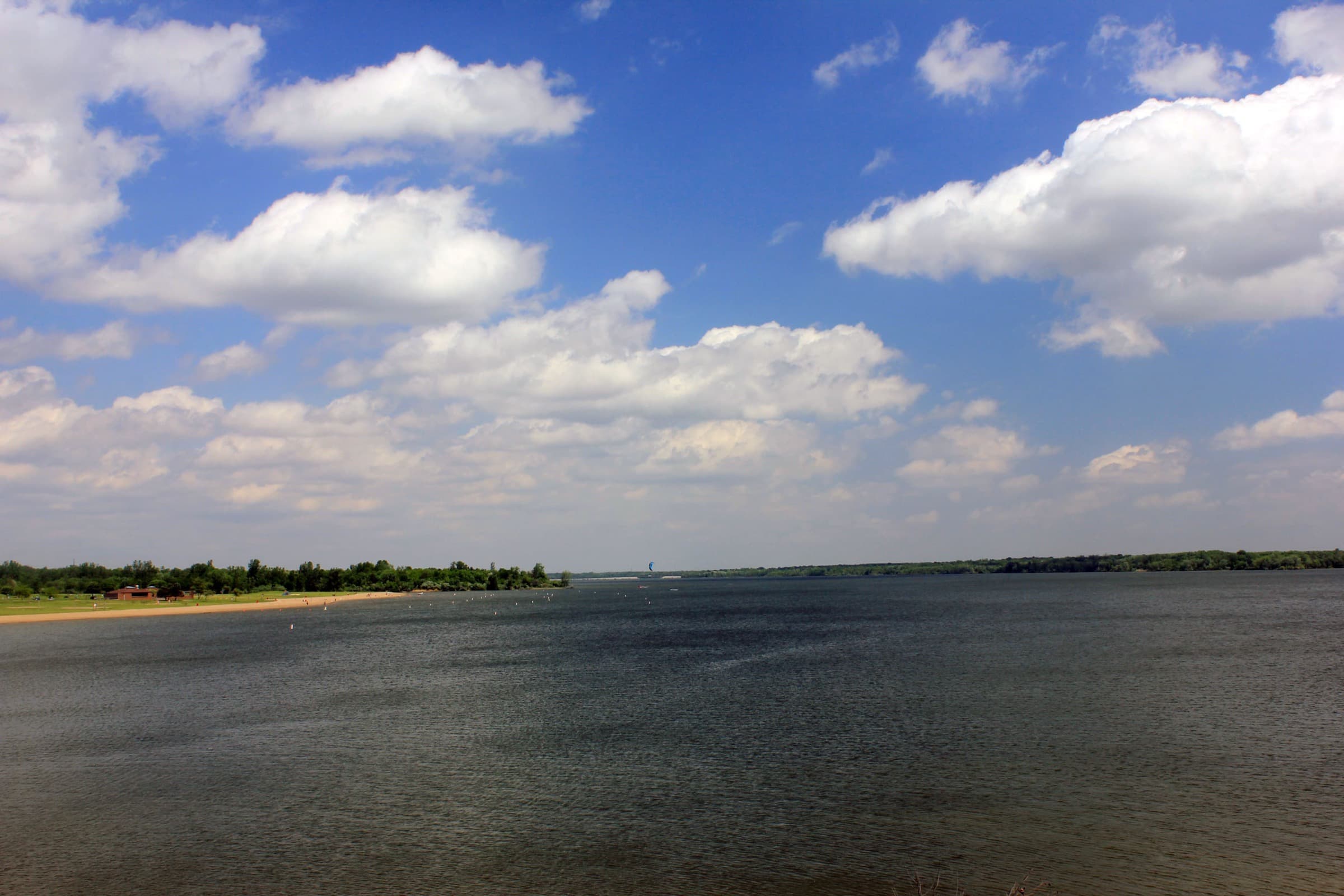 Wide view of Alum Creek Lake and its shoreline under a blue sky, seen from the dam