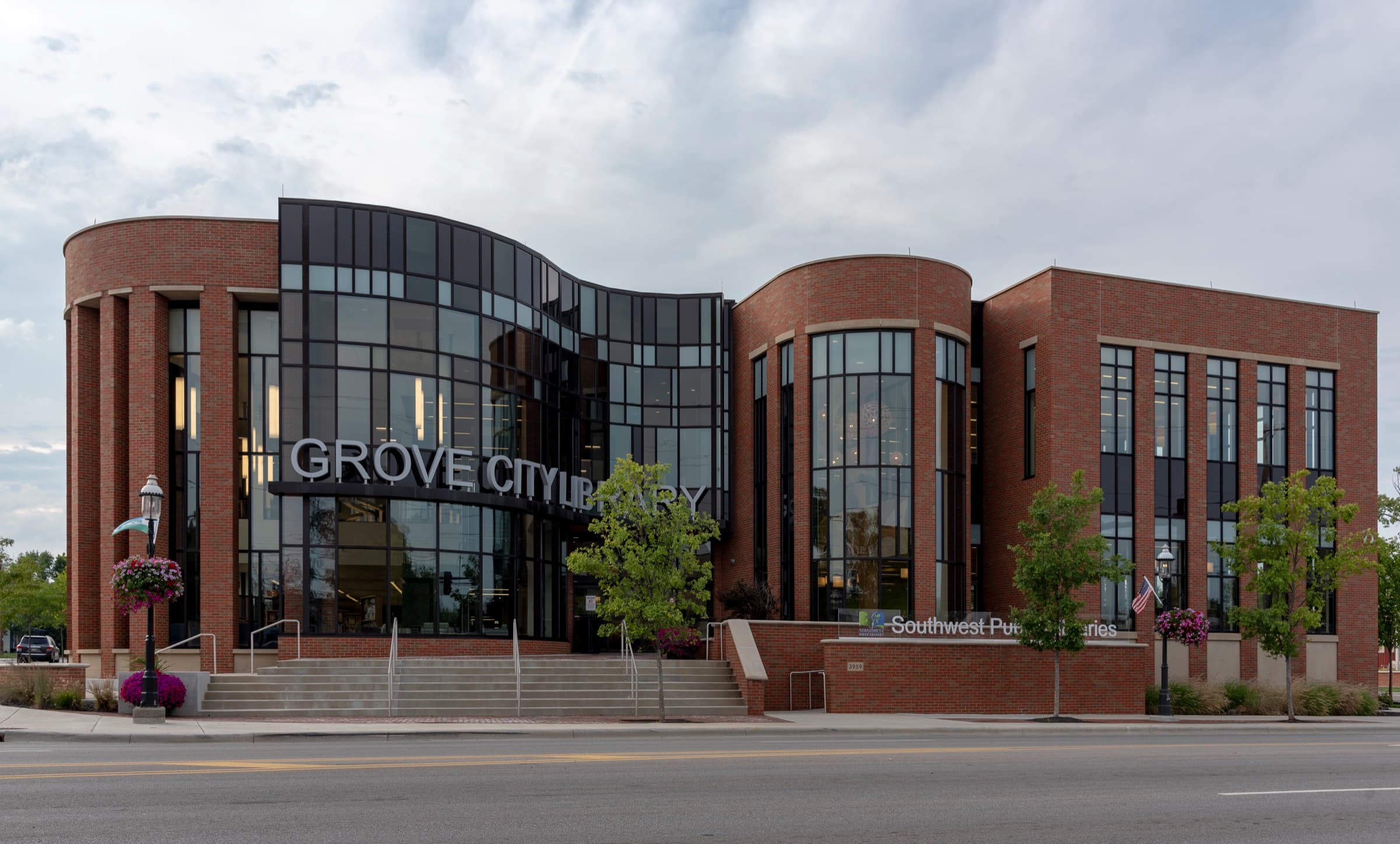 The modern glass-and-brick Grove City Library in the Town Center, with hanging flower baskets on the lampposts